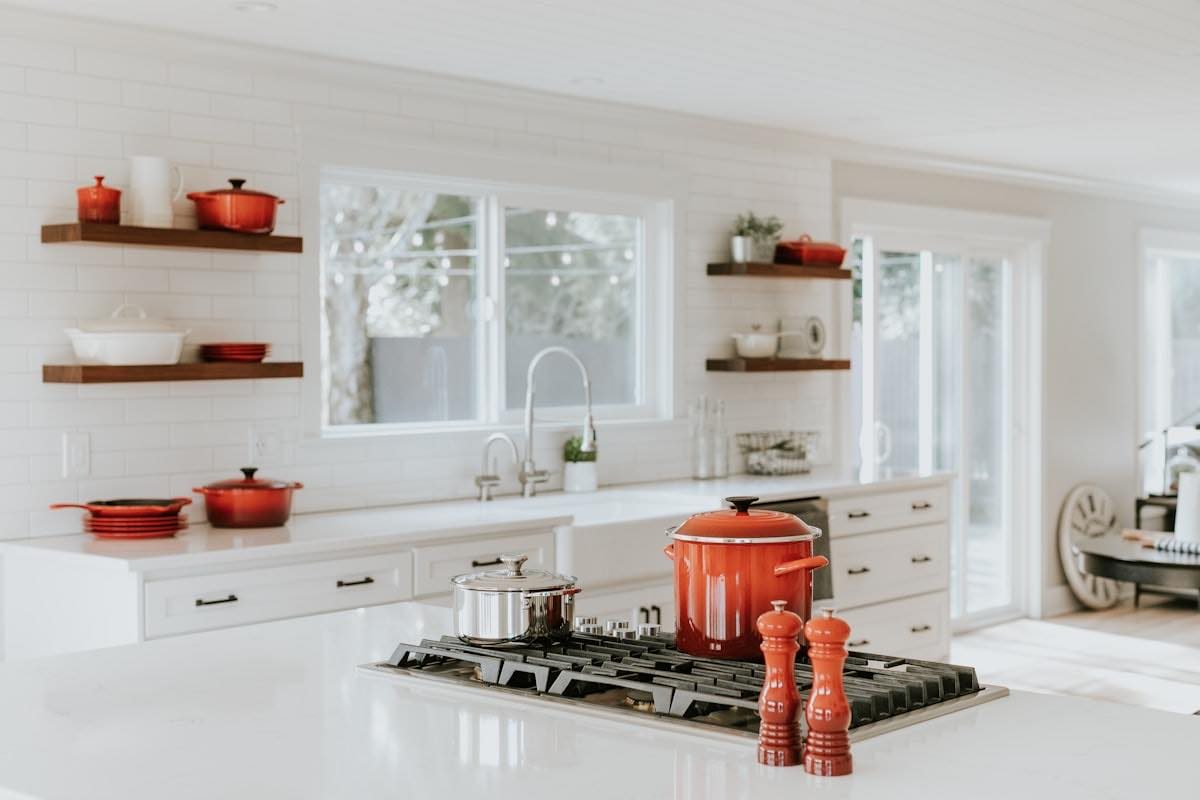 A bright kitchen with a gas hob, open shelving and a window over the sink.
